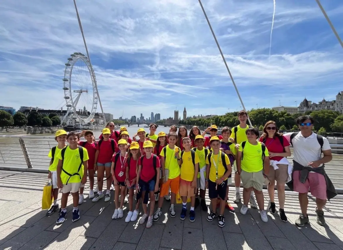 Bambini in maglia gialla e rossa su un ponte a Londra con il London Eye.